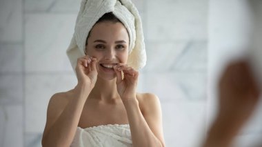 Diş ipiyle diş temizleyen genç bir kadın.