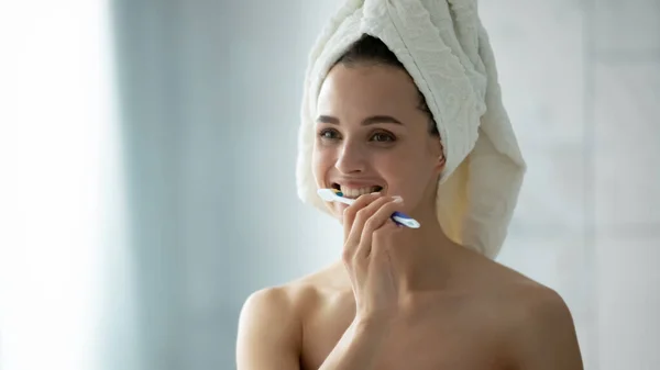 Young female brush teeth in bathroom in morning