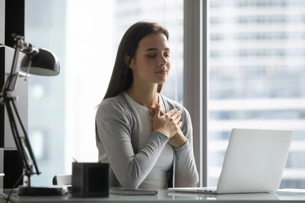Grateful young woman feel thankful meditating at work