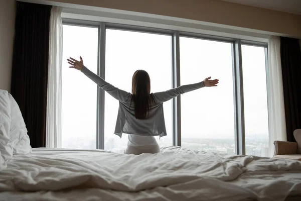 Wanita muda duduk di tempat tidur peregangan di pagi hari — Stok Foto