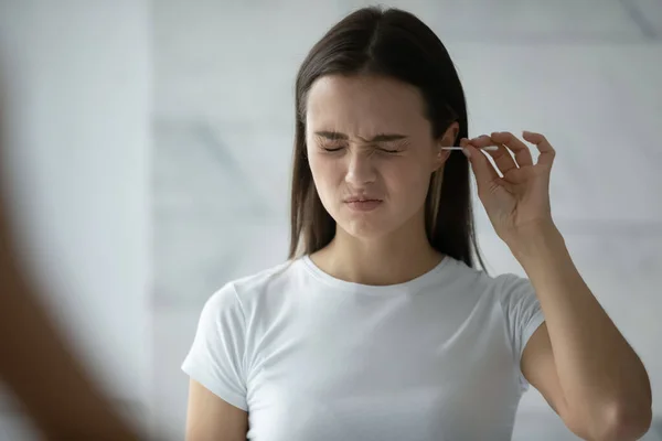 Fiatal nő tisztító fül pamut bottal — Stock Fotó