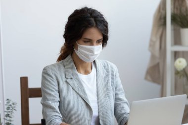 Ofiste bilgisayar üzerinde çalışan virüs koruması maskeli bir iş kadını..