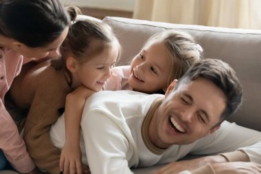 Dört kişilik neşeli bir aile kanepede birlikte eğleniyor..