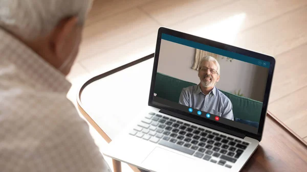 Senior man talking with 50s friend by video call