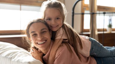 Mutlu kadın kızı sırtında yatakta yatıyor..