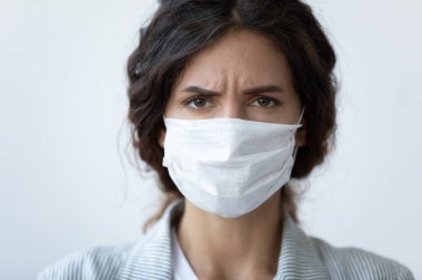 Suratı asık, mutsuz, yüzünde maske olan genç bir kadın..