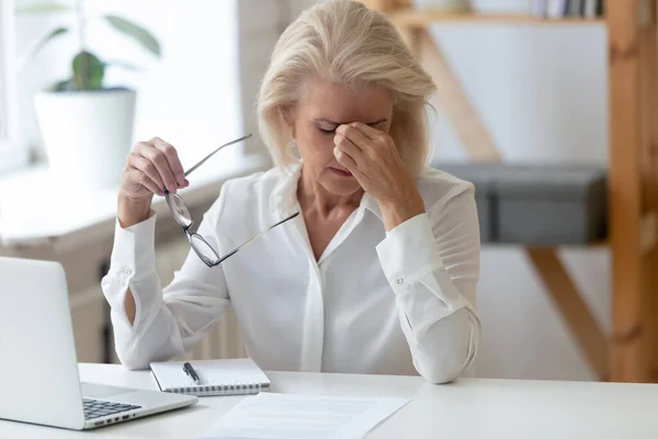 Trött 60 år gammal affärskvinna tar av glasögon. — Stockfoto