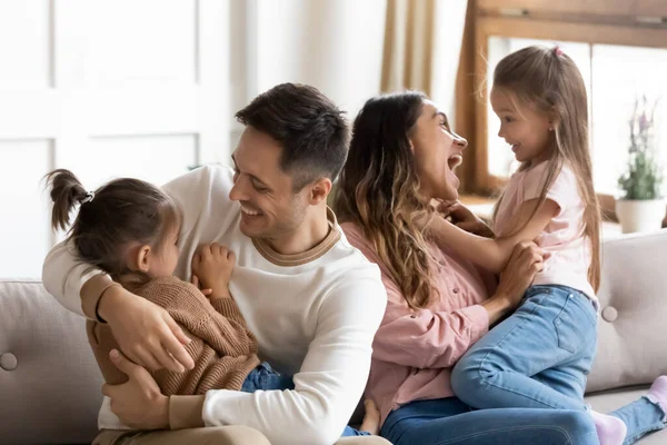 Ridendo giovane coppia di famiglia che gioca con i bambini piccoli a casa . — Foto Stock