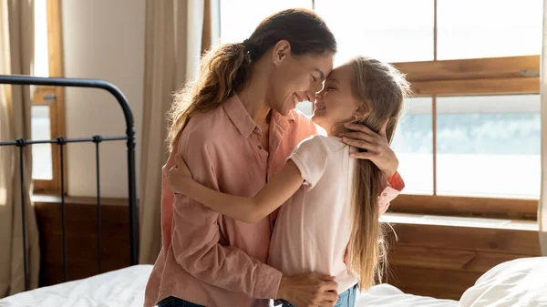 Affectionate young mother cuddling little adorable daughter in bedroom. — Stock Photo, Image