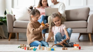 Küçük mutlu kız kardeşler yerde oyuncaklarla oynuyor..