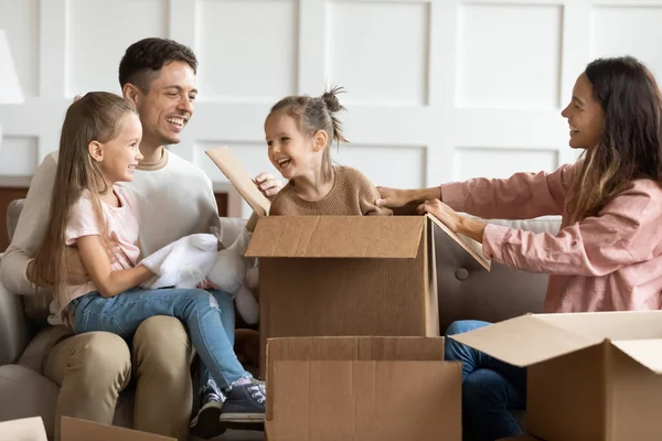 Familia alegre pareja divirtiéndose con los niños en nuevo apartamento . —  Fotos de Stock