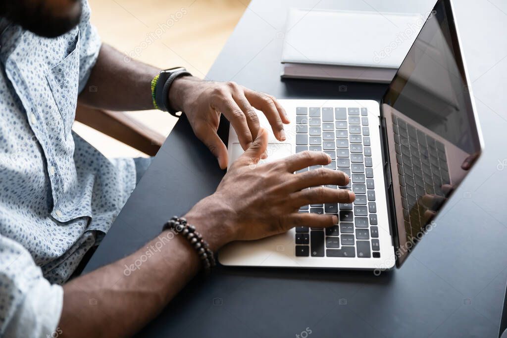 Top view of african american man texting on laptop keyboard