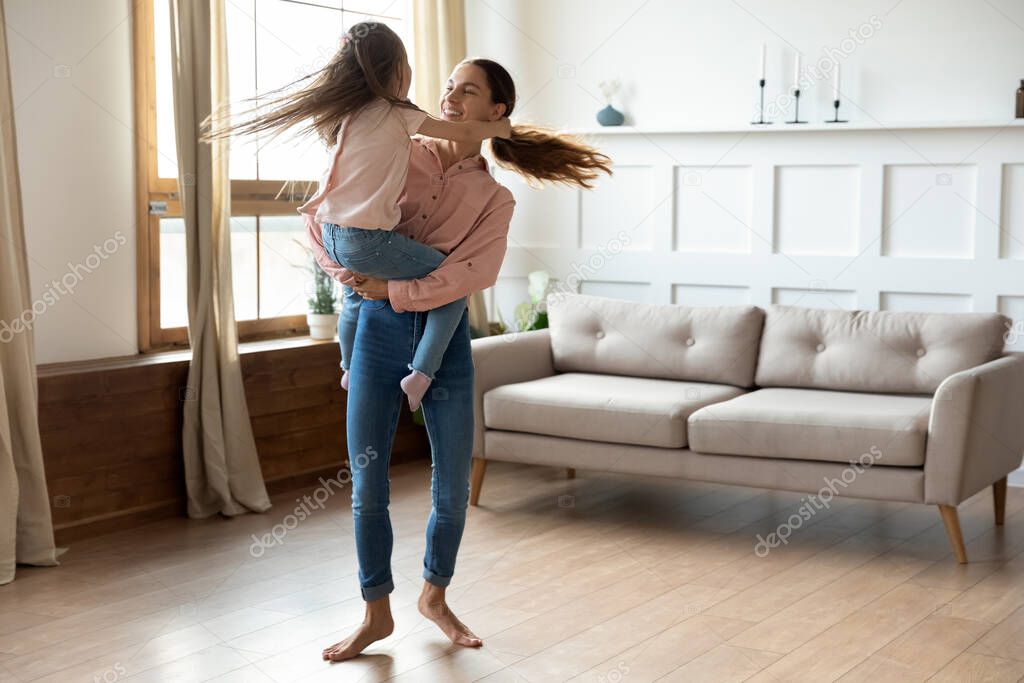 Happy mixed race mommy dancing to music with daughter.