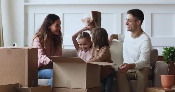 Petits enfants souriants aidant heureux jeunes parents de couple déballer des effets personnels . — Video