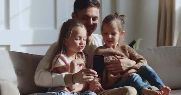 Papa souriant montrant des applications mobiles éducatives aux jeunes enfants . — Video