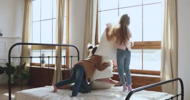 Unbekümmerte junge Frau kämpft mit Kindern im Schlafzimmer gegen Kopfkissen. — Stockvideo