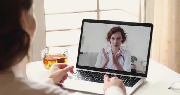 Vrouwelijke patiënt video bellen vrouw arts op laptop scherm — Stockvideo