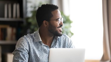 Happy young mixed race man distracted from job, looking aside.