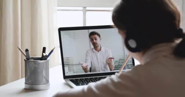 Over de schouder van de student het dragen van een koptelefoon kijken naar online webinar — Stockvideo