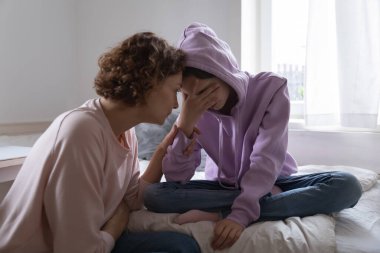 Endişeli anne evde ağlayan depresyondaki genç kızı rahatlatıyor.