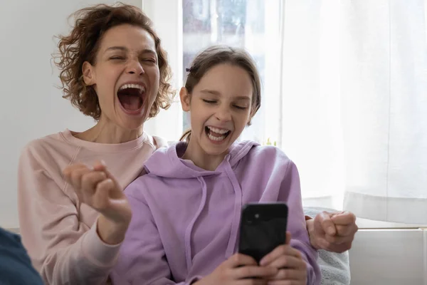 Emocionada mamá y la hija adolescente ganando con el teléfono inteligente —  Fotos de Stock
