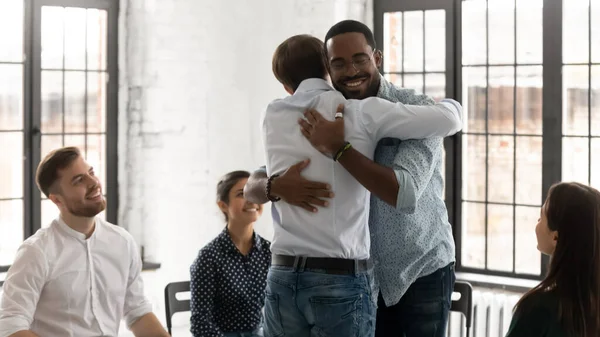 Felices abrazos de jóvenes comprometidos en la formación de motivación en grupo —  Fotos de Stock