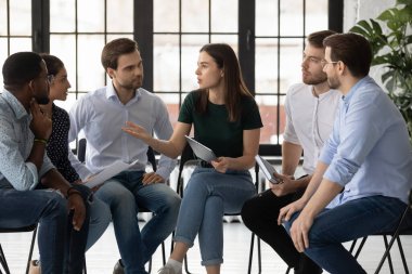 Çeşitli iş adamları toplantıda çember halinde oturup beyin fırtınası yapıyorlar.