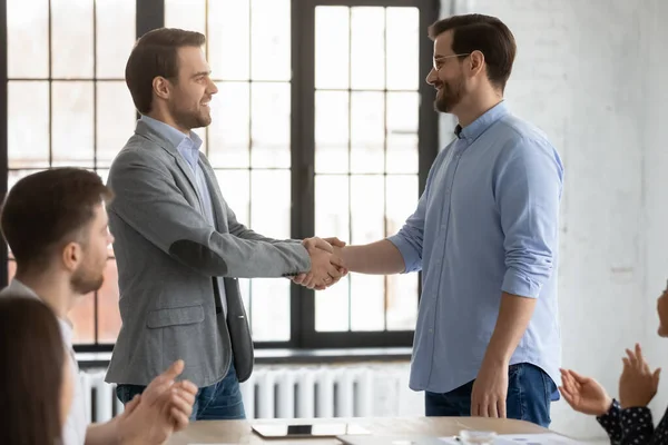 Happy boss shake hand greeting employee with promotion