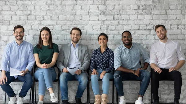 Portrait of happy multiracial candidates sit in row in hallway — Stock Photo, Image