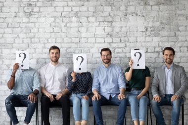 Gülümseyen erkek adaylar, röportajdan önce bilinmeyen kişilerin arasında otururlar.