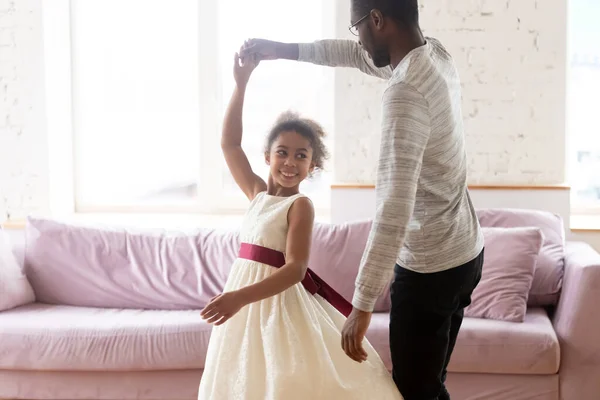 Amante padre afroamericano cogido de la mano de adorable hija bailando . — Foto de Stock