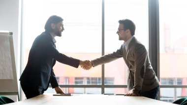 Smiling male partners handshake greeting at meeting clipart