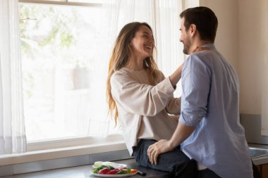Tezgahta oturan gülümseyen genç bayan, kocanla sohbet ediyor..
