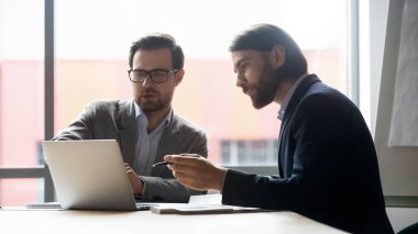 Erkek meslektaşlarım dizüstü bilgisayarda birlikte çalışırken beyin fırtınası yaptılar.