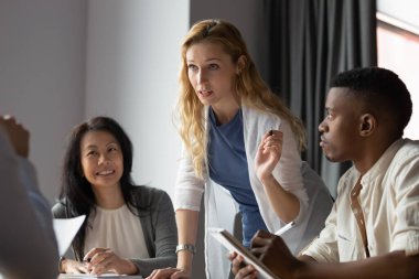 Motive olmuş kadın patron brifingde iş arkadaşlarıyla beyin fırtınası yapıyor.