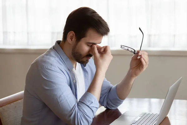 Stressed young businessman taking off glasses, suffering from eyes strain. — Stock Photo, Image