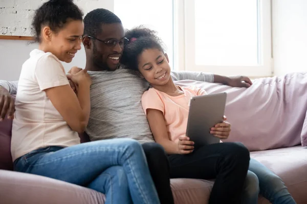 Feliz pareja afroamericana mirando la pantalla de la tableta con su hija . — Foto de Stock