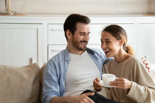 Aufgeregtes Familienpaar ruht sich auf Sofa mit Tassen Kaffee aus. — Stockfoto