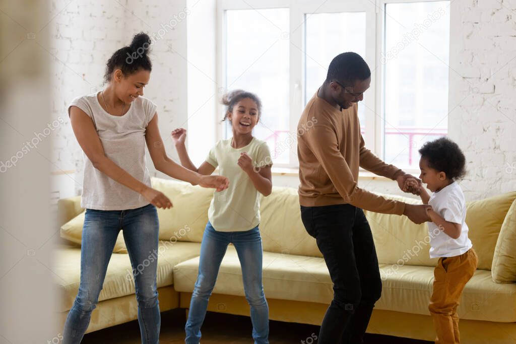 Happy african american mother and father with two children dancing.