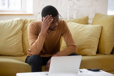 Hesaplama için hesap makinesi ve dizüstü bilgisayar kullanan üzgün bir adam.