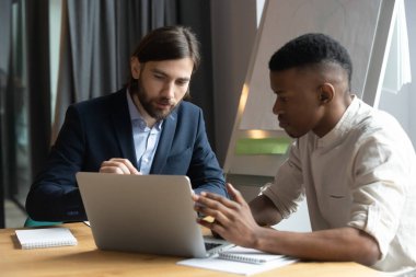 Çeşitli erkek iş arkadaşları brifingde dizüstü bilgisayarda birlikte çalışıyorlar.