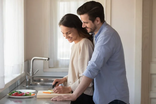 Amare affettuosi sposi novelli millenari preparare il pasto insieme a casa . — Foto Stock