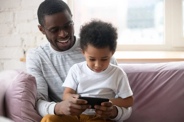 Smiling African American father with little son playing game. — Stock Photo, Image