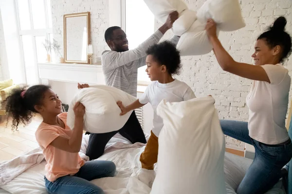 Familia afroamericana feliz con almohadas para niños lucha y ríe . —  Fotos de Stock