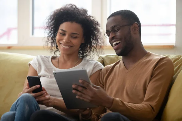 Riendo afroamericano hombre y mujer pareja mirando el teléfono inteligente —  Fotos de Stock
