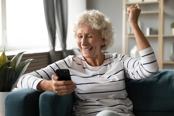 Podekscytowana starsza kobieta korzystająca z telefonu, świętująca dobry nowy — Zdjęcie stockowe