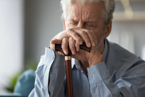 Chiudi triste uomo anziano che si tiene per mano sul bastone da passeggio — Foto Stock