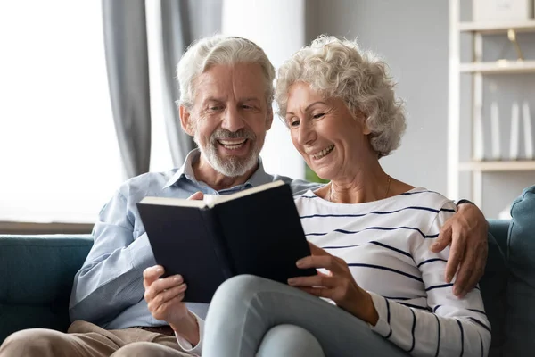 Sonriendo hombre y mujer maduros disfrutando de la literatura juntos —  Fotos de Stock