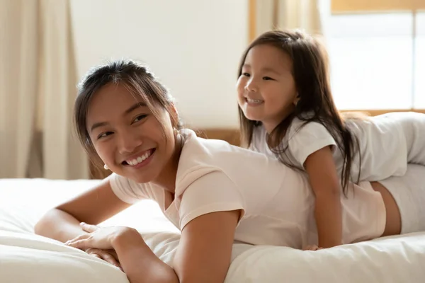 Kleine dochter en aziatische moeder spelen terwijl liggend op bed — Stockfoto