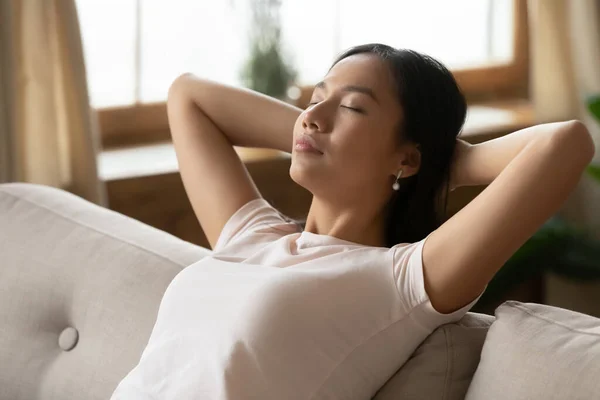 Asyalı kadın ellerini başının arkasına koyup kanepede dinleniyor. — Stok fotoğraf